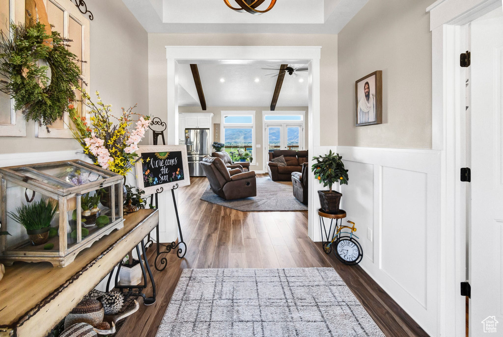 Entryway with beam ceiling, a wainscoted wall, a ceiling fan, and dark wood finished floors