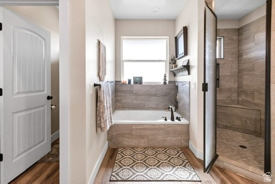 Full bath featuring a garden tub, wood finished floors, and a tile shower