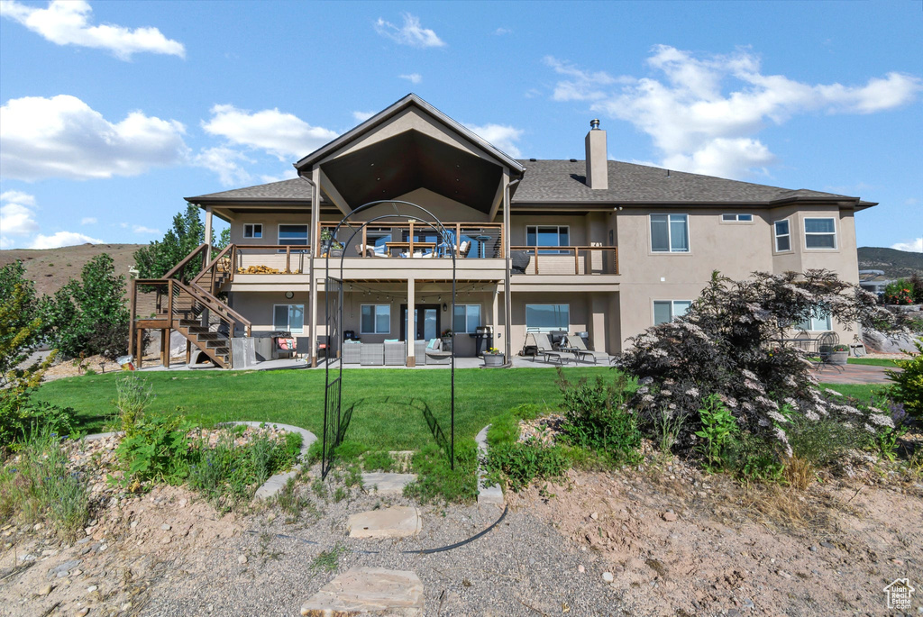 Back of property featuring stucco siding, outdoor lounge area, a patio area, a lawn, and a chimney