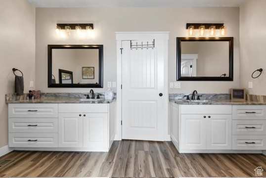 Full bath featuring wood finished floors and two vanities