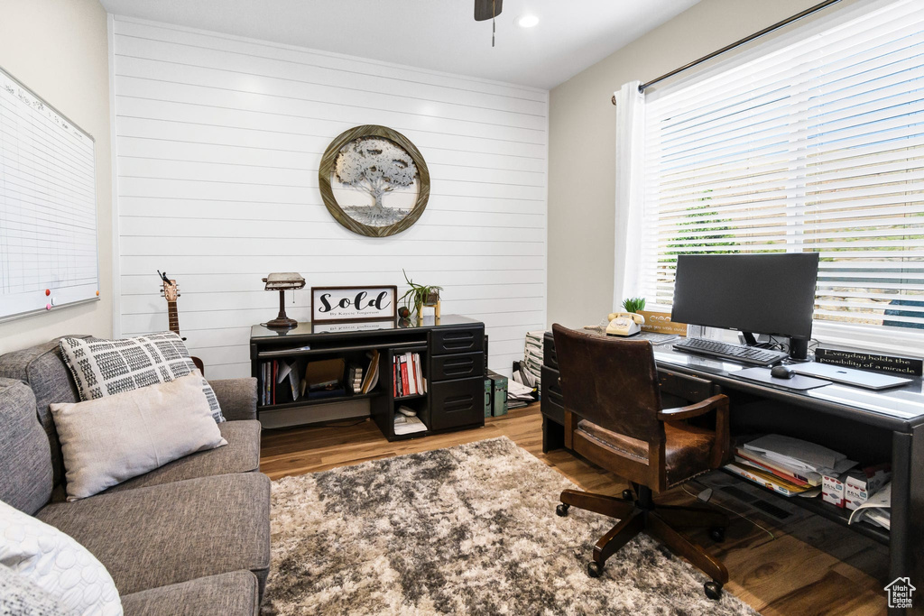 Office with wood finished floors, wooden walls, and ceiling fan