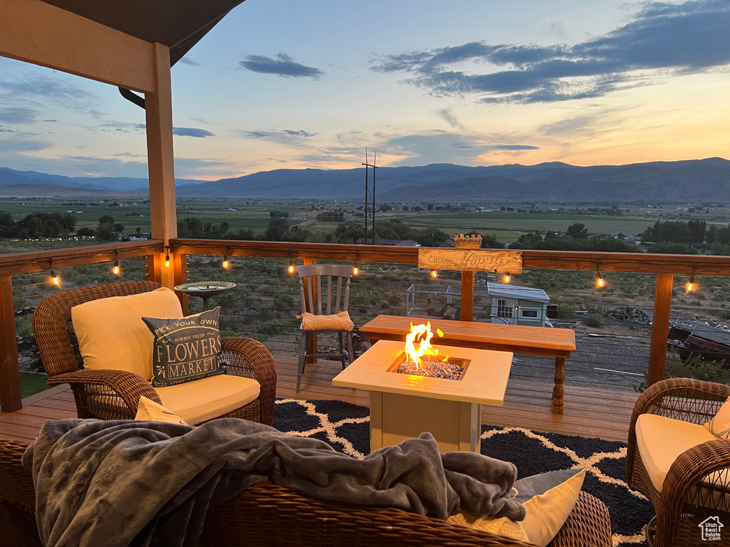Deck at dusk featuring an outdoor fire pit and a mountain view
