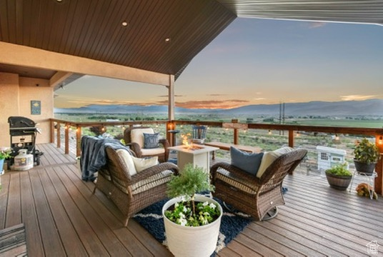Deck at dusk with area for grilling and an outdoor living space with a fire pit