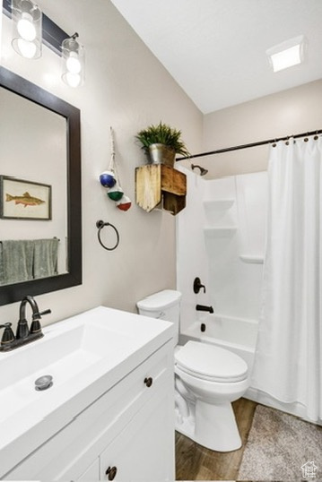 Full bathroom with vanity, wood finished floors, and shower / bath combo with shower curtain