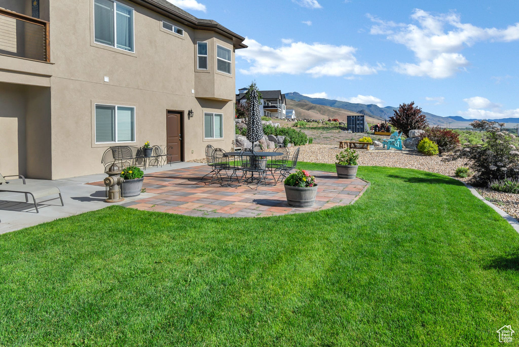 View of green lawn featuring a mountain view and a patio area