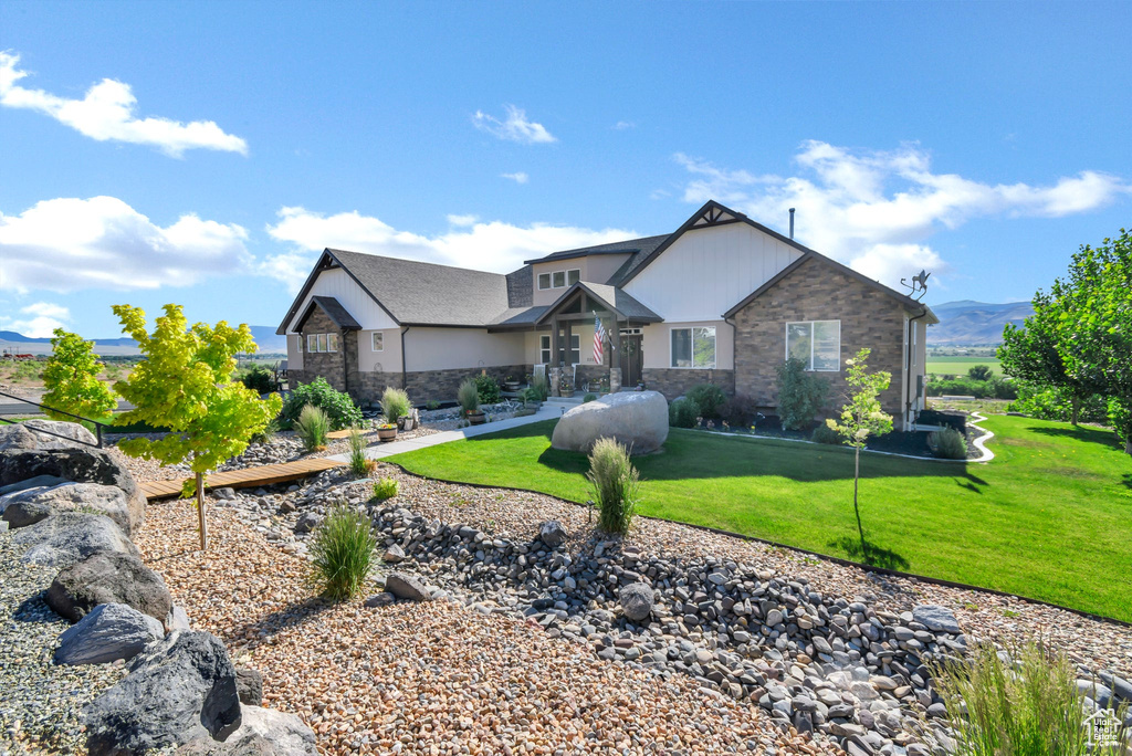 View of front facade featuring stone siding, a front yard, and a mountain view