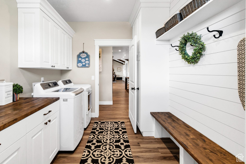 Washroom with washing machine and dryer, cabinet space, and wood finished floors