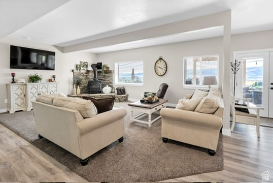 Living area featuring wood finished floors, a wood stove, and plenty of natural light