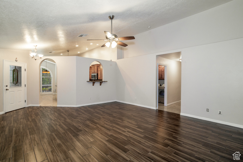 Unfurnished living room featuring ceiling fan, washer / clothes dryer, a chandelier, wood finished floors, and lofted ceiling