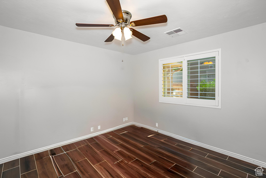 Spare room featuring dark wood-type flooring and a ceiling fan