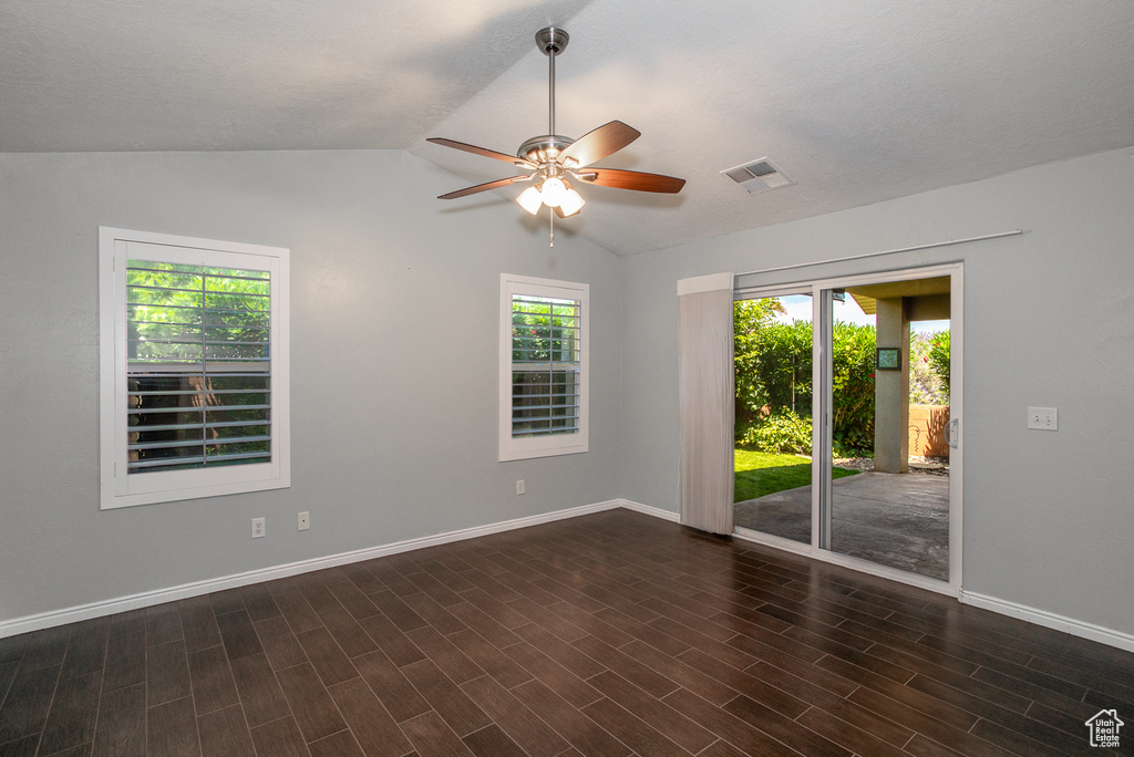 Empty room featuring a ceiling fan, vaulted ceiling, and dark wood finished floors