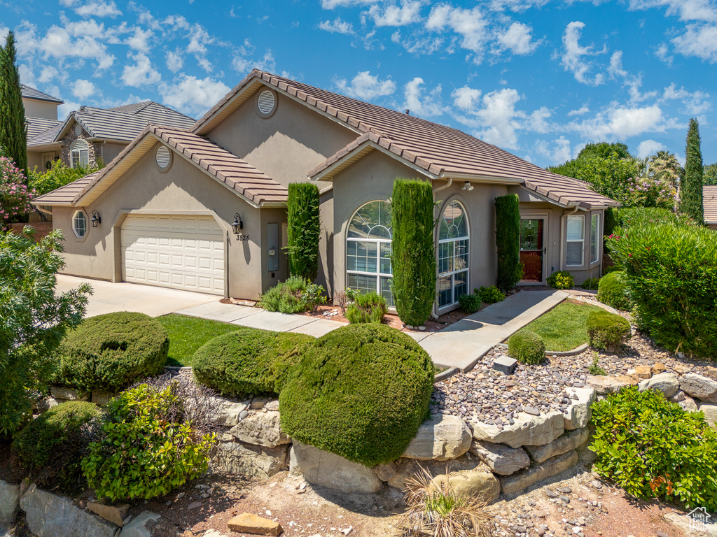 Ranch-style home with an attached garage, stucco siding, driveway, and a tile roof