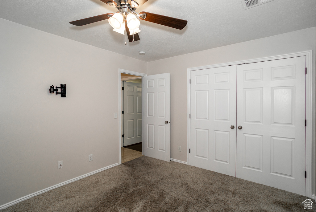 Unfurnished bedroom with carpet flooring, a closet, and a ceiling fan