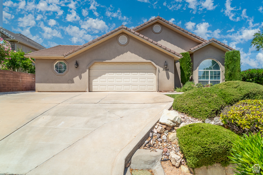 Mediterranean / spanish home with driveway, an attached garage, and stucco siding