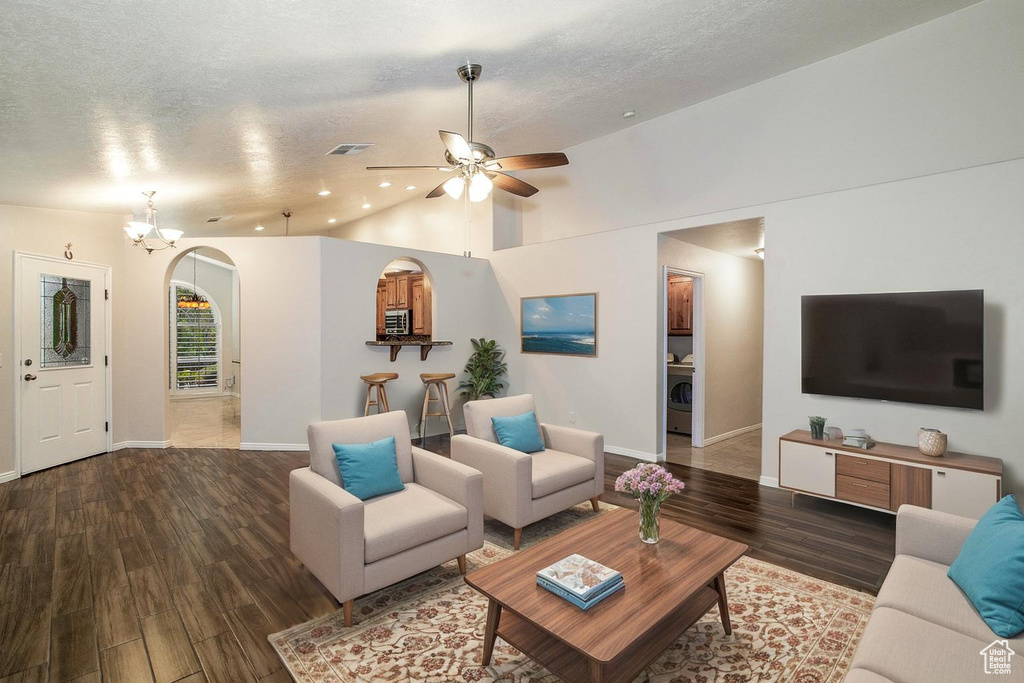 Living area featuring wood finished floors, arched walkways, ceiling fan, lofted ceiling, and a chandelier