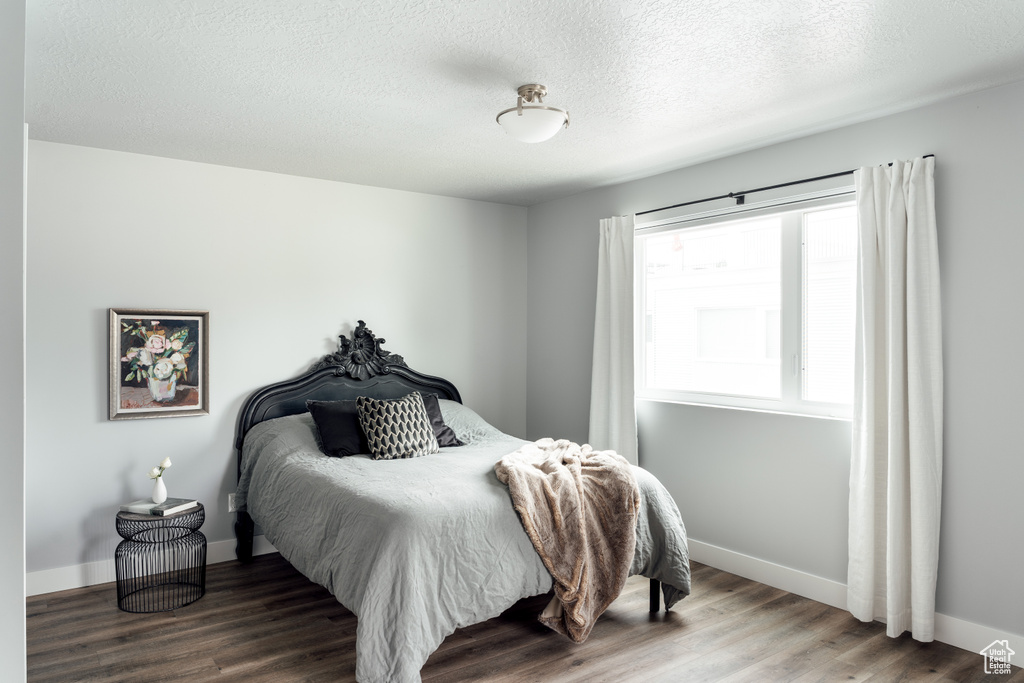 Bedroom featuring wood finished floors, baseboards, and a textured ceiling