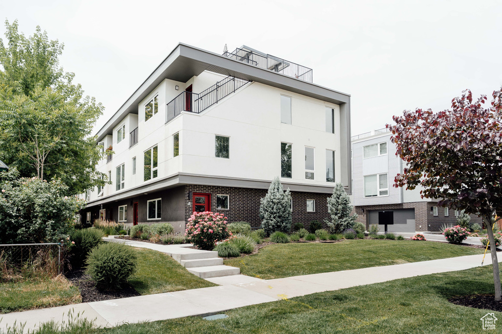 View of front facade featuring stucco siding, brick siding, and a front lawn