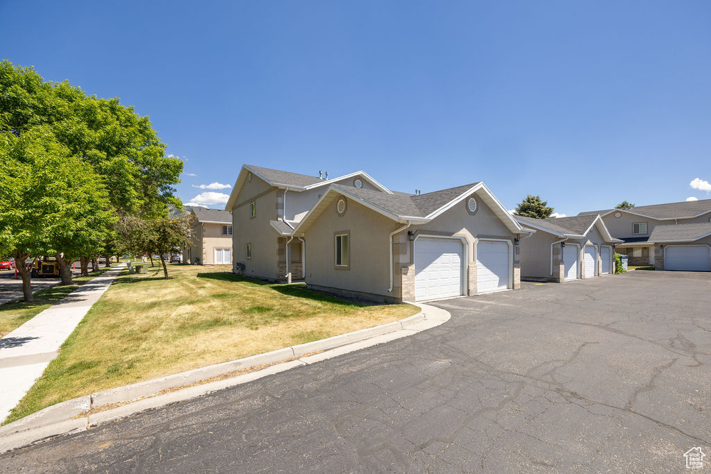 View of front facade with a garage, stucco siding, a front lawn, and driveway