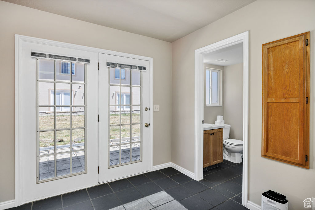 Doorway with dark tile patterned floors and baseboards