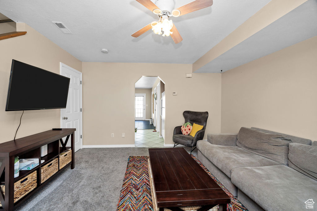 Carpeted living area featuring arched walkways and a ceiling fan