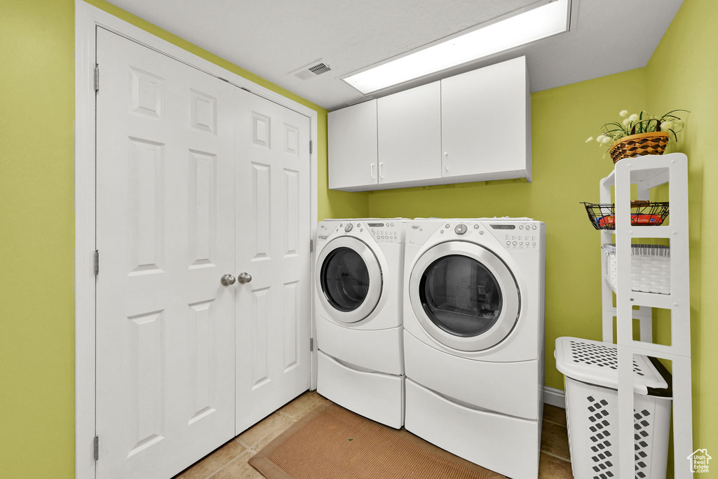 Laundry room with cabinet space, washer and dryer, and light tile patterned floors