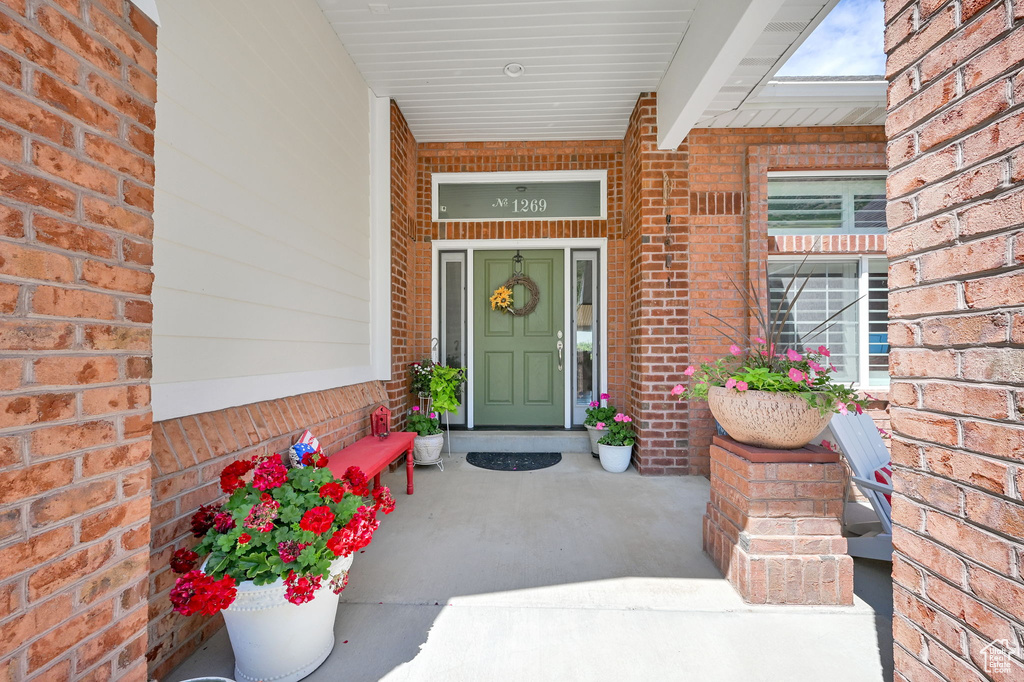 Doorway to property with brick siding and covered porch