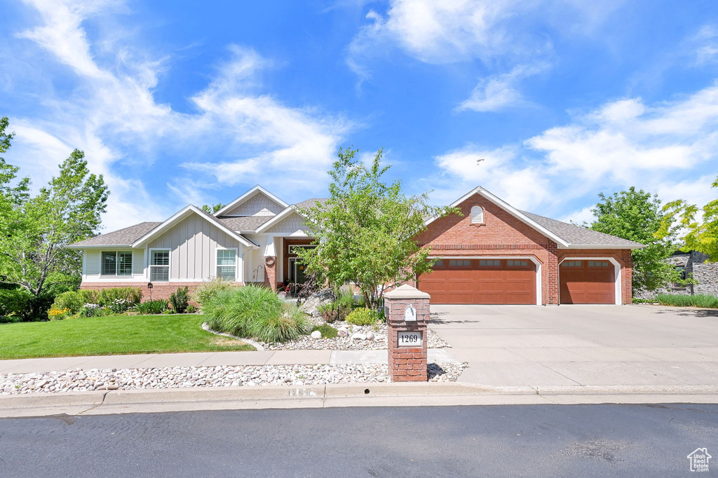 View of front of house featuring brick siding, board and batten siding, a garage, and driveway