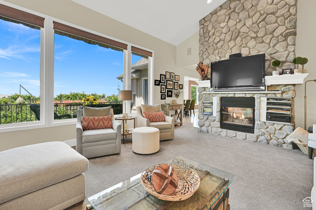 Carpeted living area featuring a stone fireplace and lofted ceiling