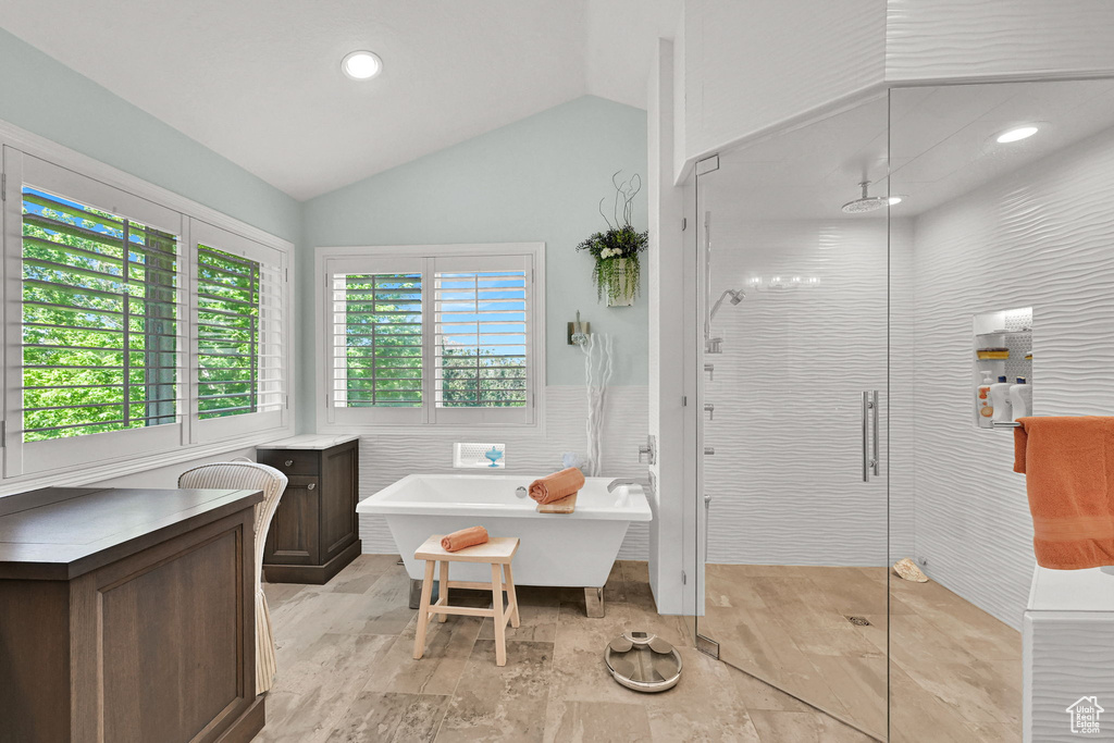 Full bathroom featuring a shower stall, a soaking tub, lofted ceiling, tile walls, and recessed lighting