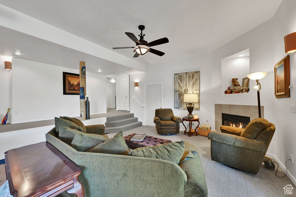 Living room featuring a tile fireplace, ceiling fan, recessed lighting, stairs, and wood finished floors