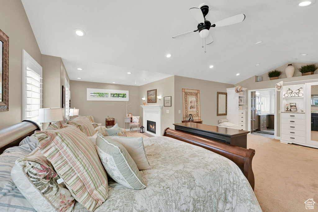 Bedroom featuring multiple windows, light carpet, lofted ceiling, recessed lighting, and a lit fireplace