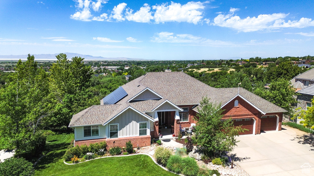 View of front of property featuring brick siding, board and batten siding, an attached garage, driveway, and a front yard