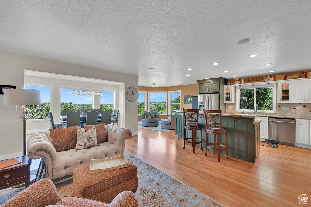 Living area with light wood-style flooring, plenty of natural light, recessed lighting, and a textured ceiling