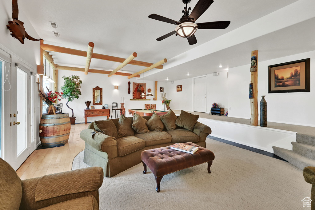 Living room featuring light wood finished floors, a ceiling fan, and beam ceiling