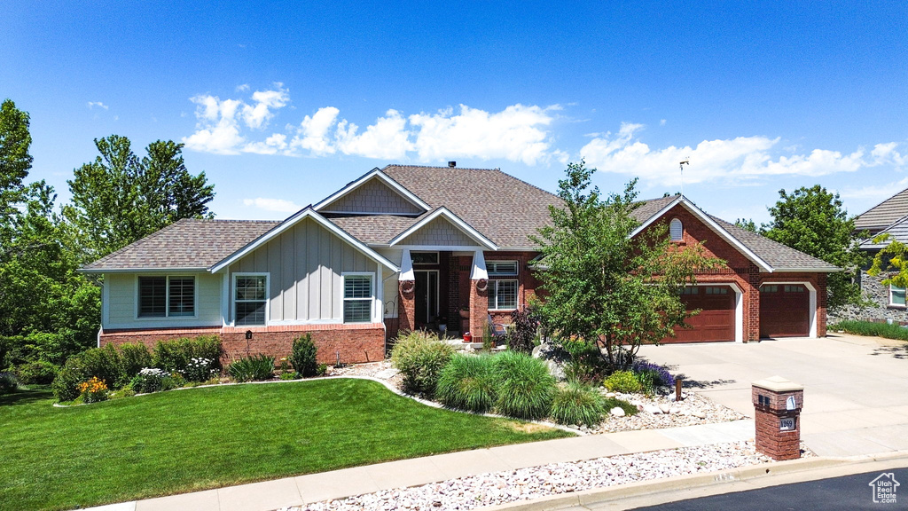 Craftsman inspired home with board and batten siding, brick siding, driveway, an attached garage, and a front lawn