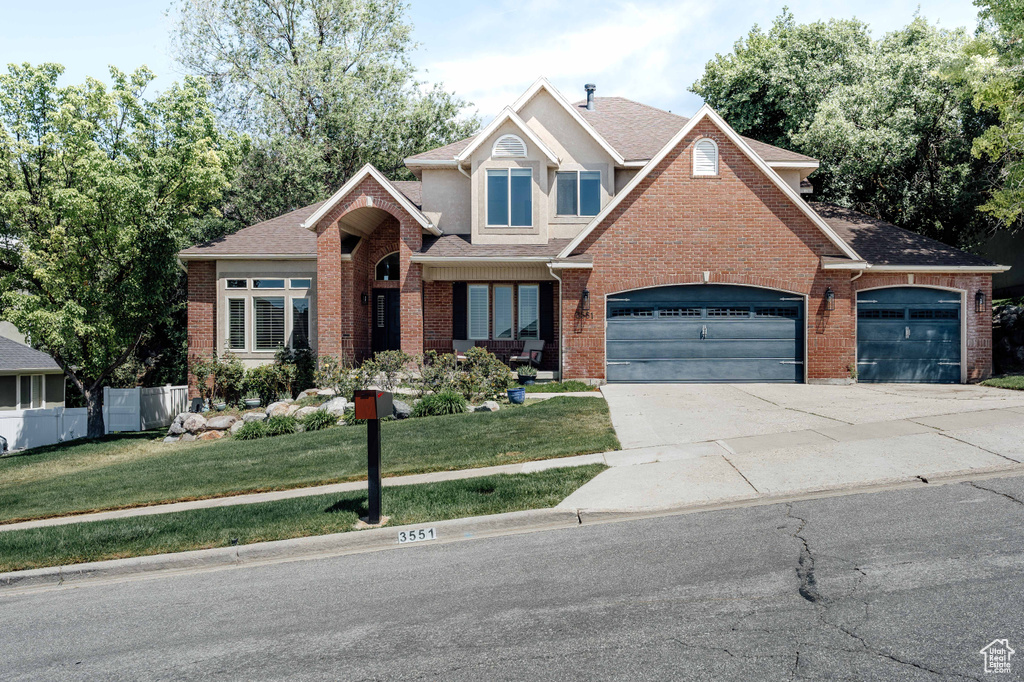Traditional-style house featuring roof with shingles, brick siding, an attached garage, and driveway
