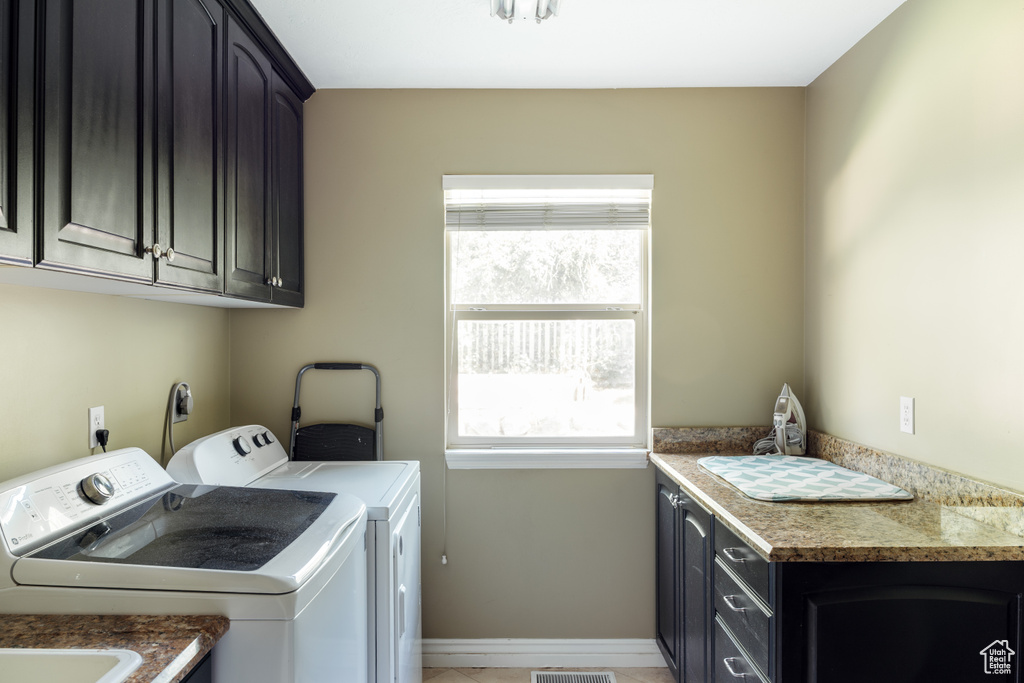 Washroom featuring cabinet space, washer and clothes dryer, plenty of natural light, and light tile patterned flooring