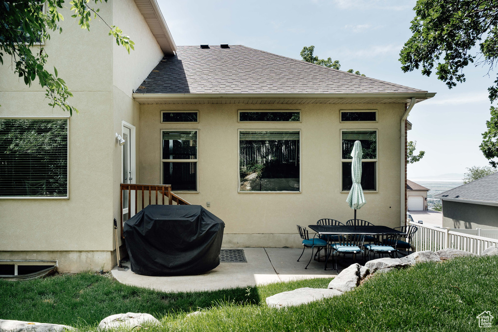 Back of house featuring a shingled roof, a patio, and stucco siding