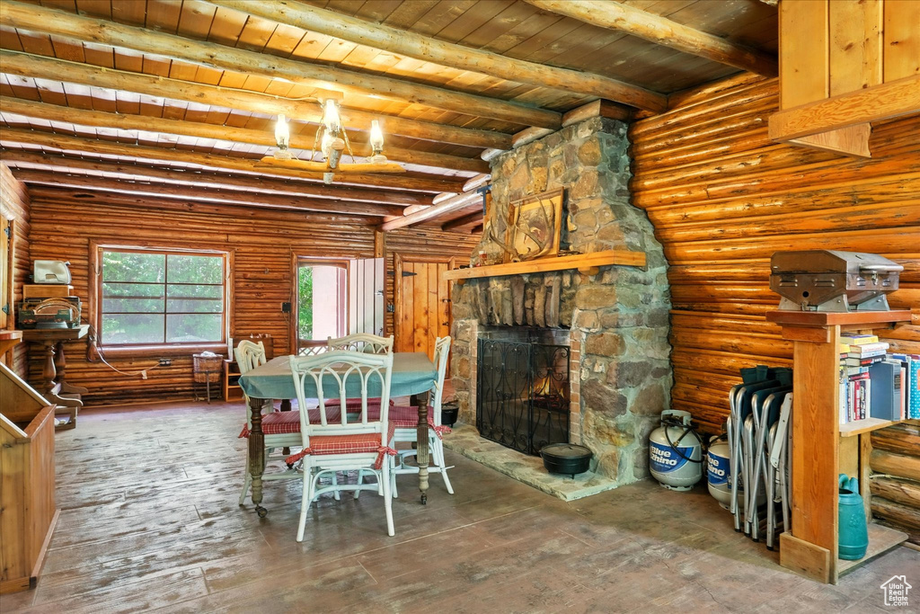 Dining area featuring a wooden ceiling with exposed beams, a fireplace, rustic walls, and wood finished floors
