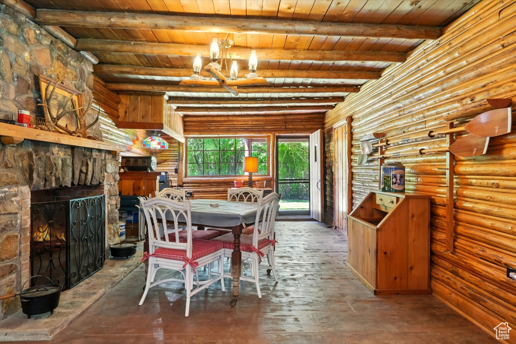 Dining room featuring a wood ceiling with exposed beams, rustic walls, a stone fireplace, and hardwood / wood-style floors