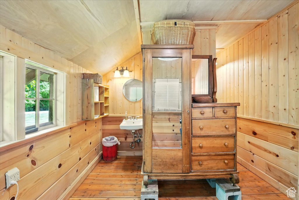 Bathroom featuring hardwood / wood-style flooring, wood walls, and vaulted ceiling