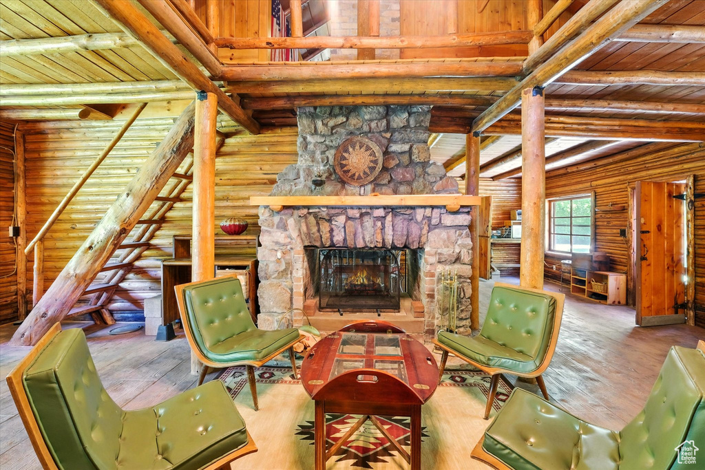 Living room with wood ceiling, log walls, wood-type flooring, and a fireplace