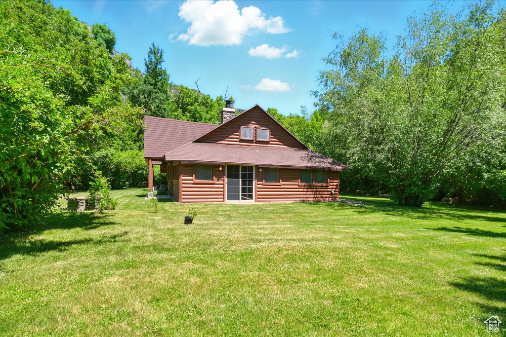 View of front of house featuring a front yard, a chimney, and a shingled roof