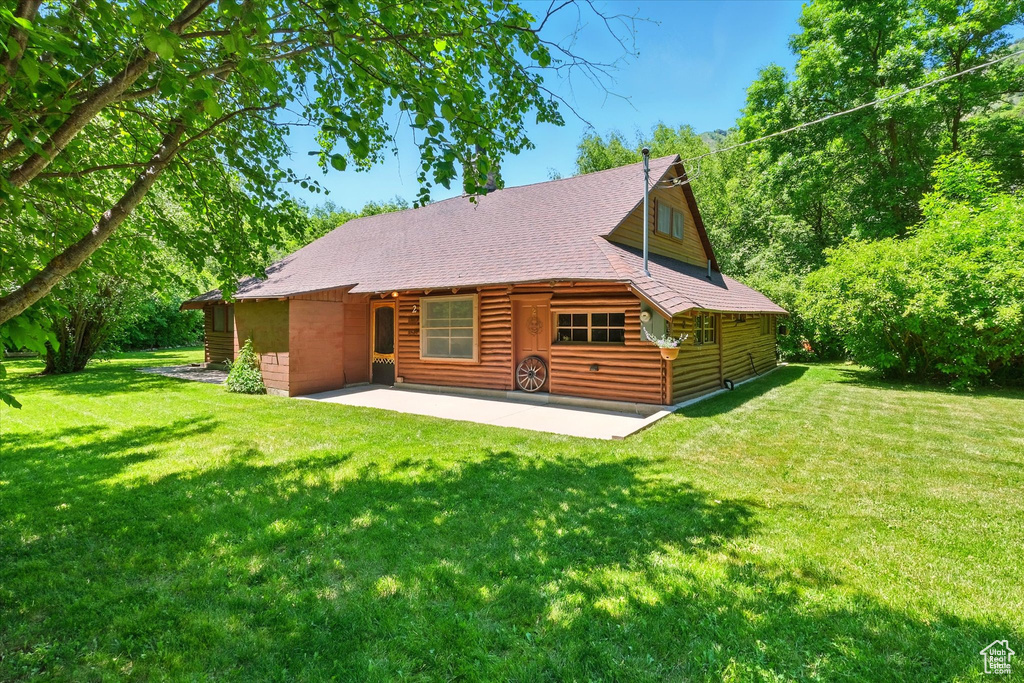 Rear view of house with a patio, a lawn, and roof with shingles