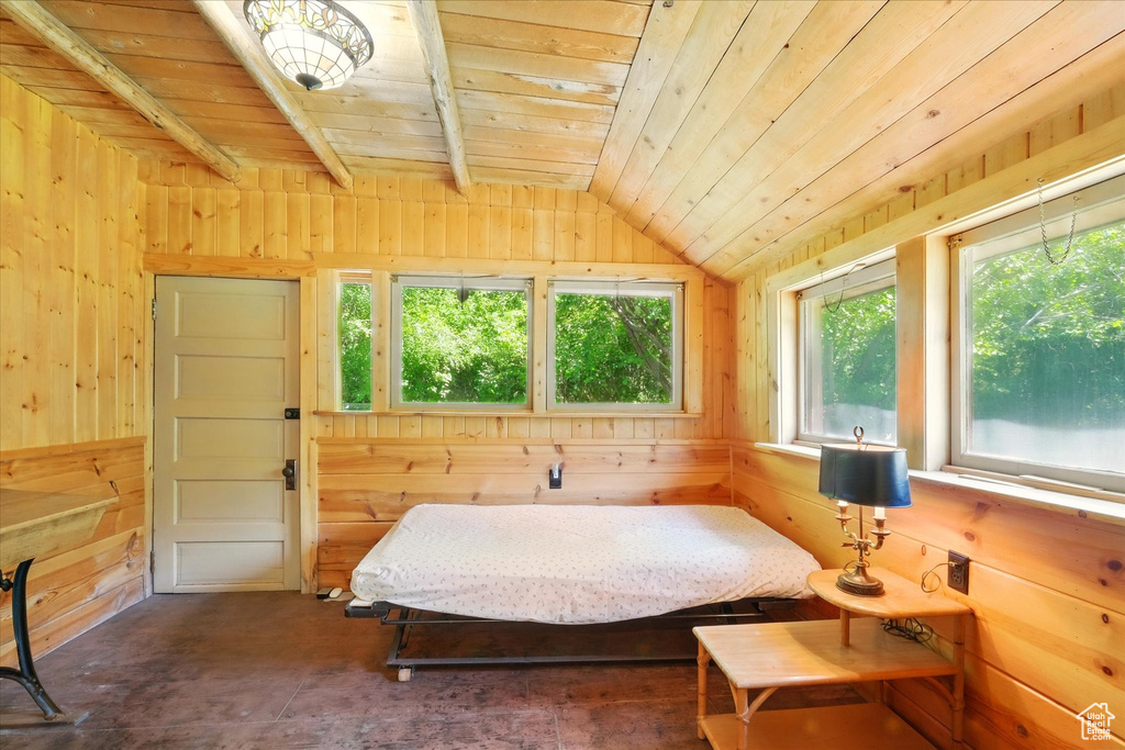 Bedroom with wooden ceiling, multiple windows, lofted ceiling, and wooden walls