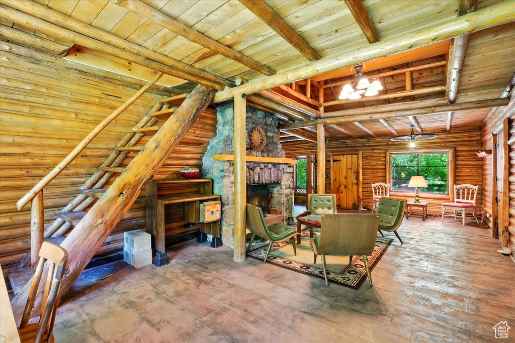Living room featuring a wood ceiling with exposed beams, a fireplace, a chandelier, wood-type flooring, and rustic walls