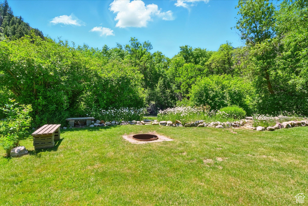 View of grassy yard with an outdoor fire pit