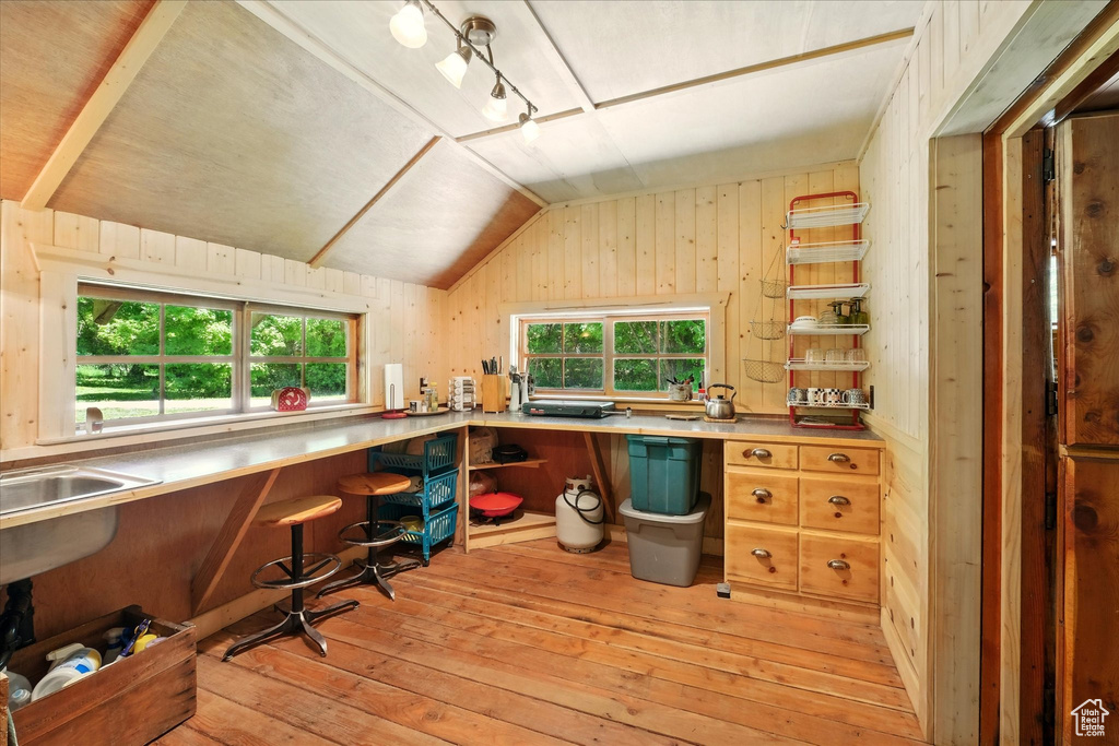 Office space with light wood finished floors, lofted ceiling, and wooden walls