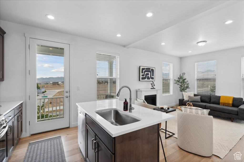 Kitchen featuring a kitchen bar, light countertops, a fireplace, a kitchen island with sink, and light wood-style flooring