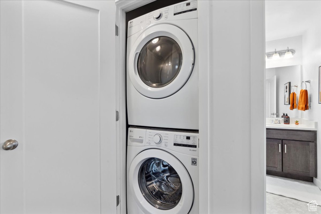 Laundry room with stacked washing machine and dryer and light tile patterned flooring